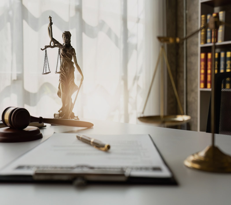 Law office desk with a bronze Lady Justice statue, scales, and a wooden gavel.