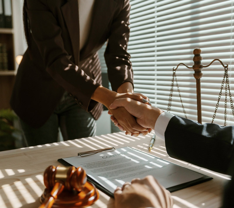 Handshake between a lawyer and client over a signed agreement.
