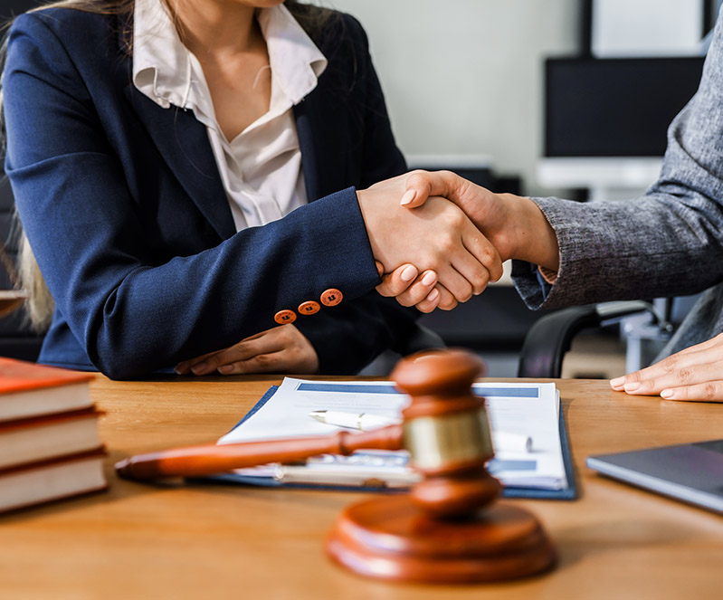 Attorney and client shaking hands over legal documents