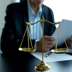 Attorney reviewing case files behind golden scales of justice.
