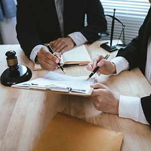 Professionals reviewing legal contract on desk with gavel; contract dispute law firm.