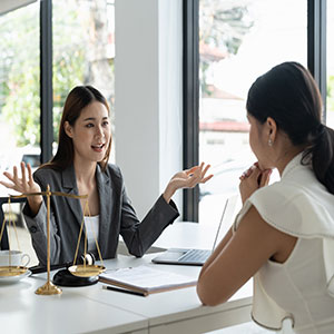 Female attorney gesturing during client consultation near legal scales; expert law firm advice.
