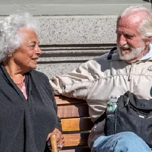 Older couple sitting together and talking on a bench outdoors